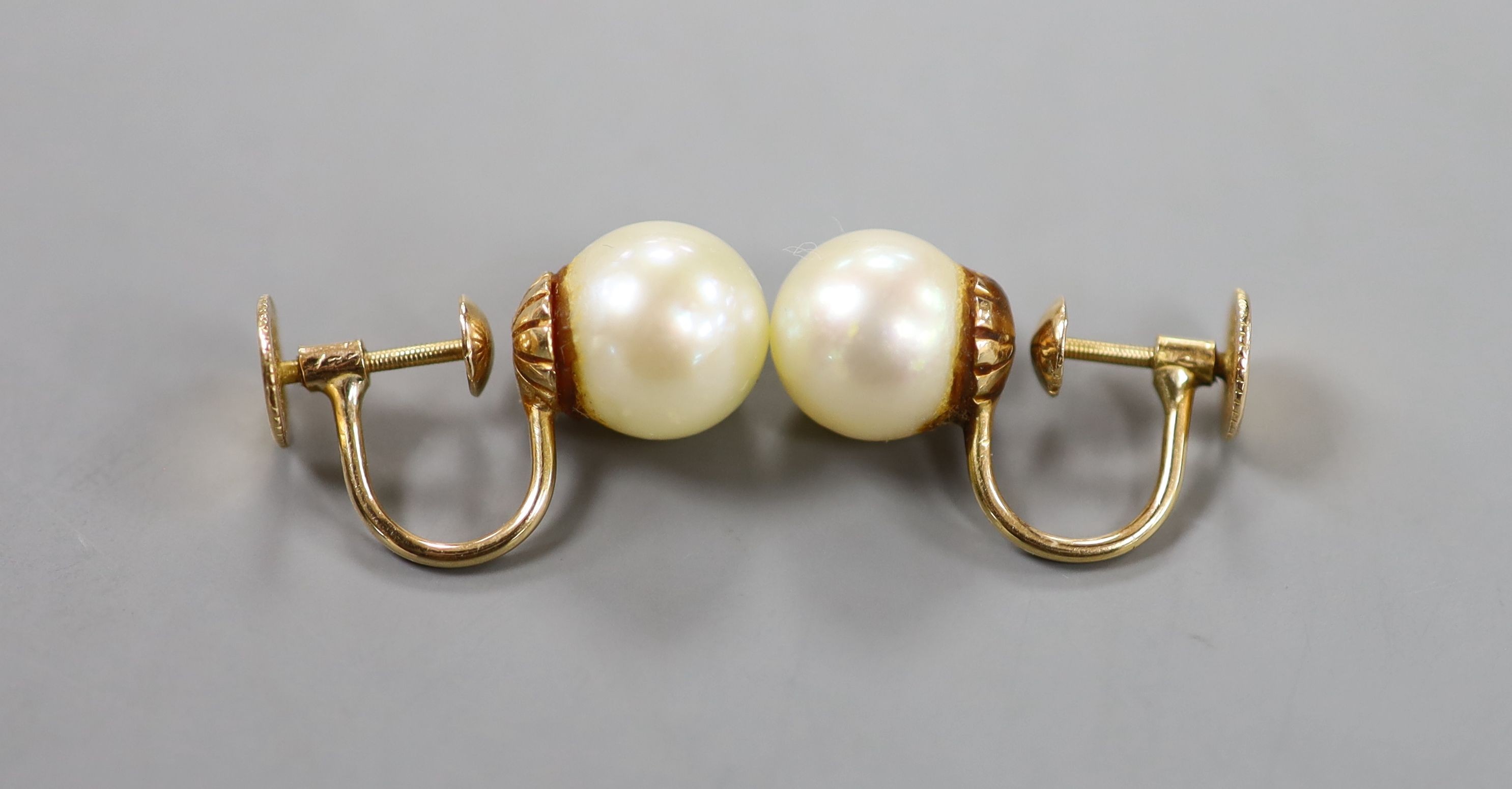 A pair of yellow metal and cultured pearl ear clips, pearl diameter 9mm, gross weight 4.1 grams.